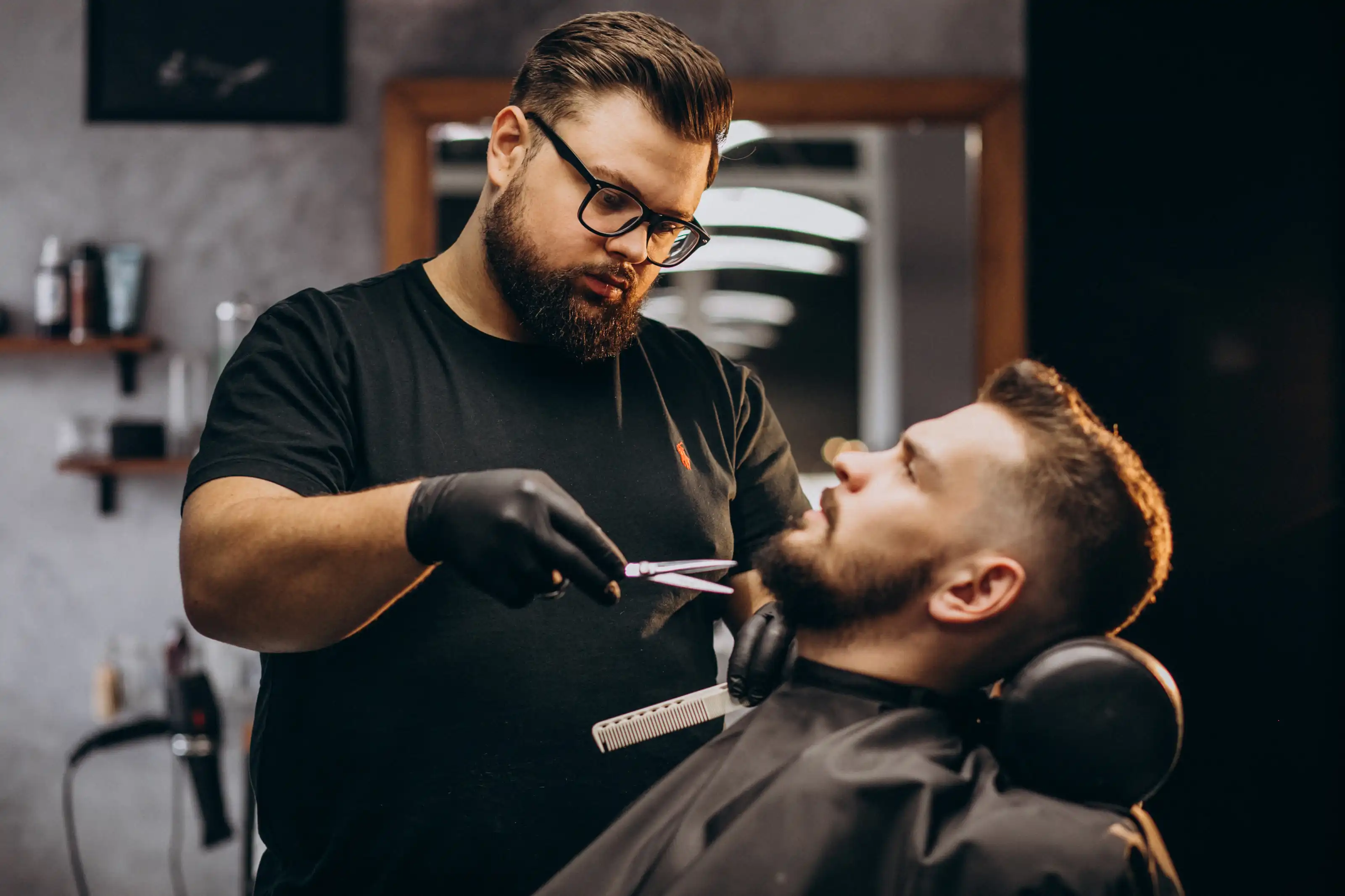 Handsome man cutting beard at a barber shop salon By senivpetro
